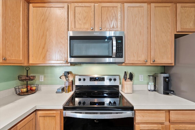 kitchen featuring light brown cabinets, electric stove, stainless steel microwave, and light countertops