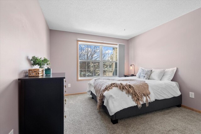 carpeted bedroom with a textured ceiling and baseboards