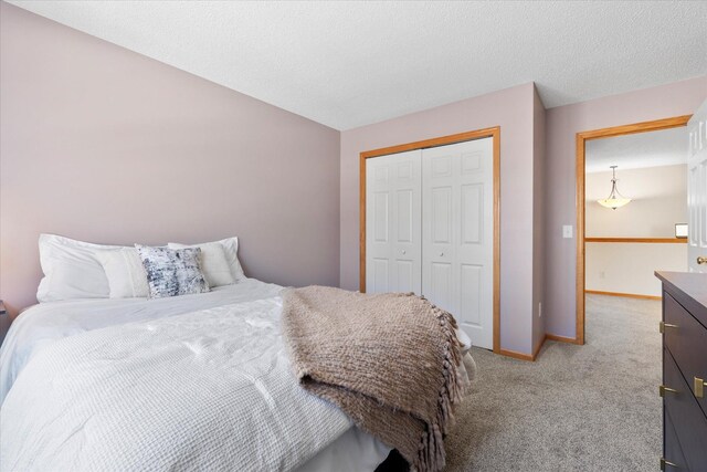 carpeted bedroom with a textured ceiling, baseboards, and a closet