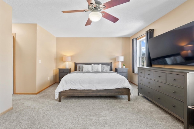 bedroom featuring a ceiling fan, light carpet, a textured ceiling, and baseboards