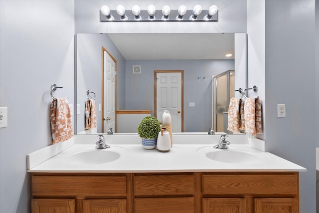 full bath with double vanity, a sink, and a shower with shower door