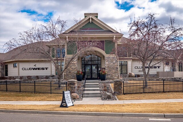 view of front facade featuring a fenced front yard, stone siding, and a garage