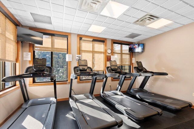 gym featuring a paneled ceiling, visible vents, plenty of natural light, and baseboards