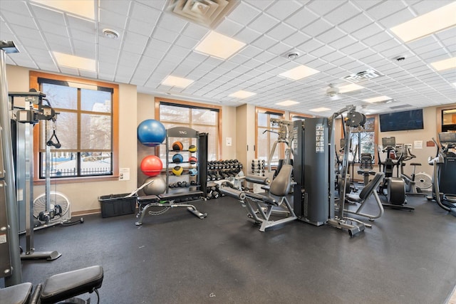 gym with a paneled ceiling, baseboards, and visible vents