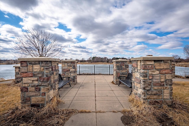 view of patio / terrace featuring a water view and fence