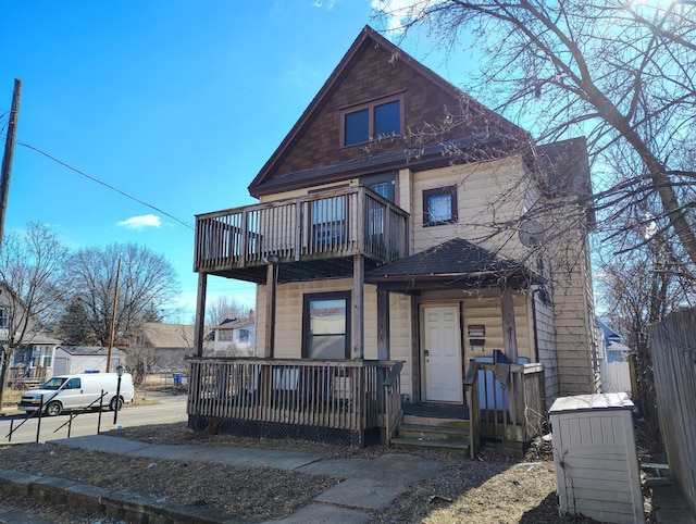 view of front facade featuring a balcony, covered porch, and fence