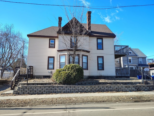 view of front of property with stairway, a chimney, and fence