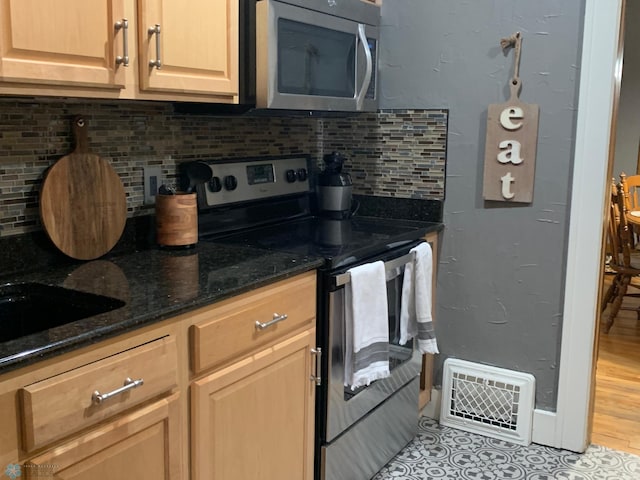 kitchen with dark stone countertops, visible vents, appliances with stainless steel finishes, and backsplash