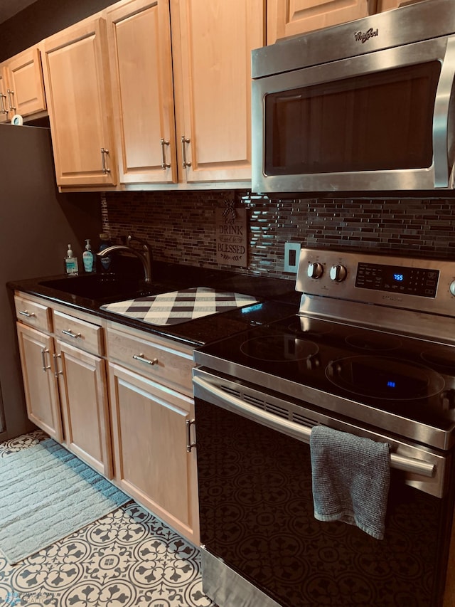 kitchen with appliances with stainless steel finishes, dark countertops, a sink, and decorative backsplash