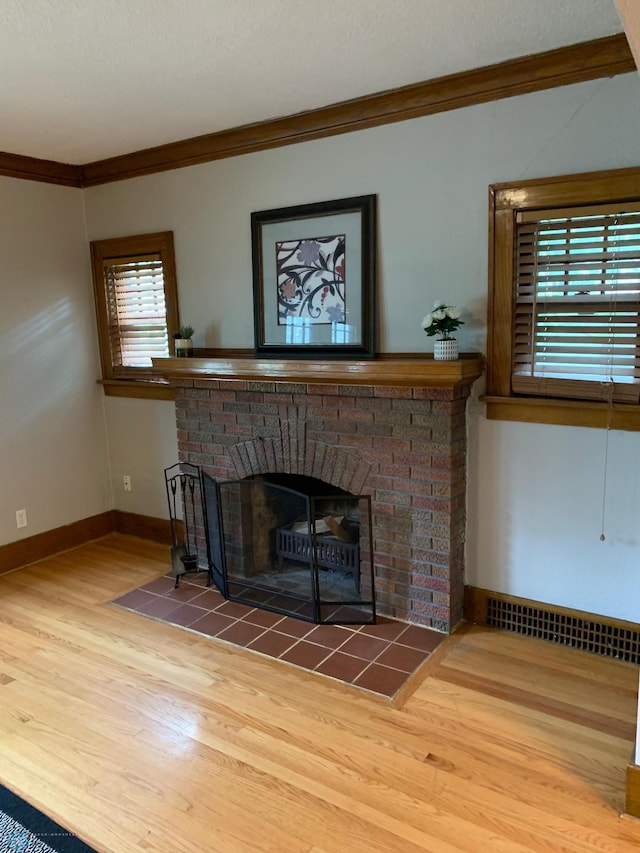 details featuring baseboards, visible vents, ornamental molding, wood finished floors, and a fireplace