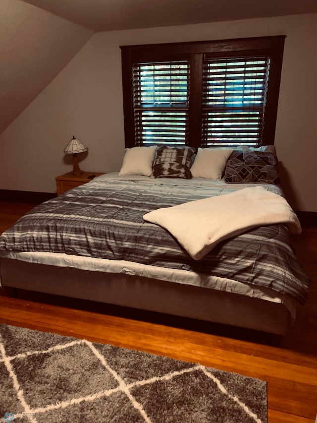 bedroom featuring lofted ceiling and wood finished floors