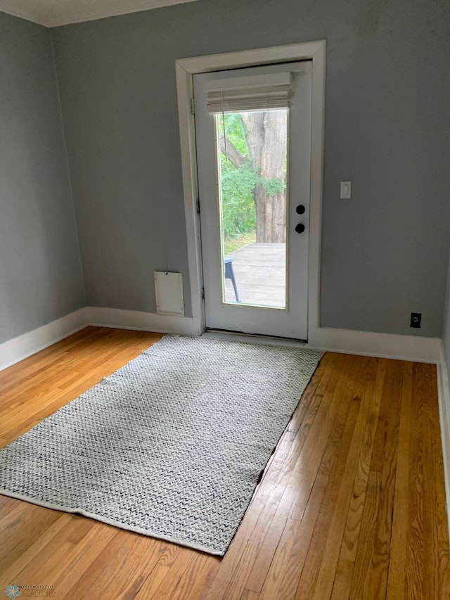 doorway with baseboards and hardwood / wood-style floors