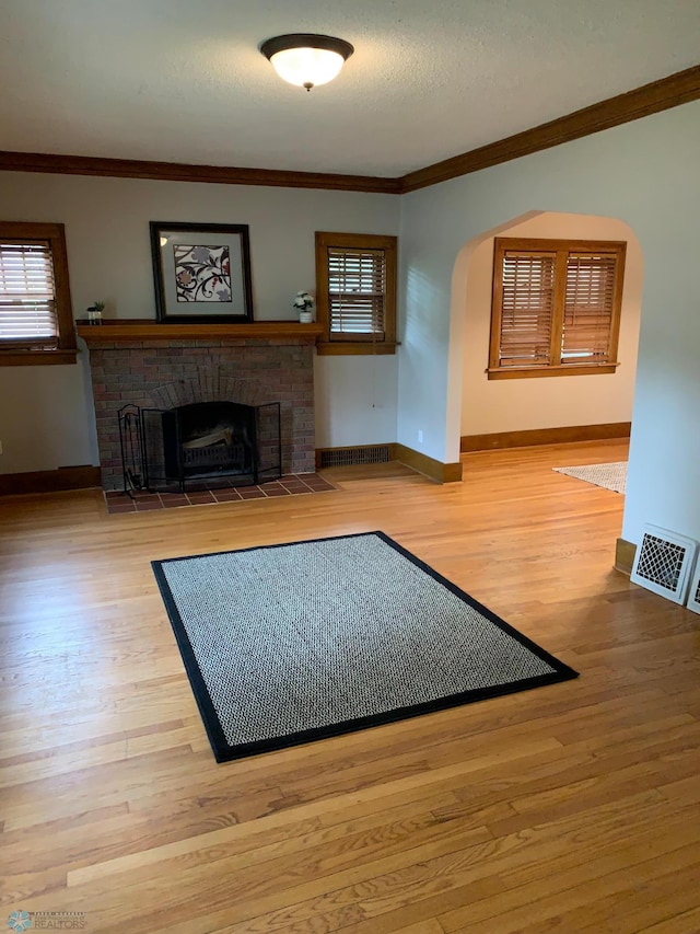 unfurnished living room featuring ornamental molding, a fireplace, wood finished floors, and visible vents