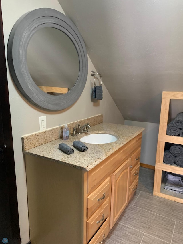 bathroom with vaulted ceiling, vanity, and baseboards