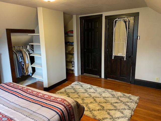 bedroom featuring baseboards, vaulted ceiling, and wood finished floors