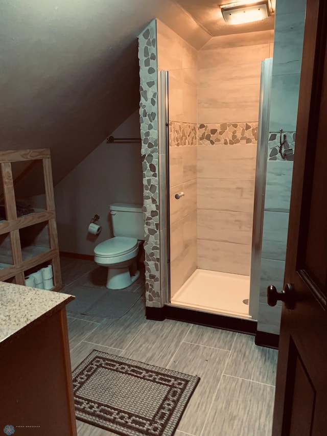 bathroom with toilet, a stall shower, vaulted ceiling, and vanity