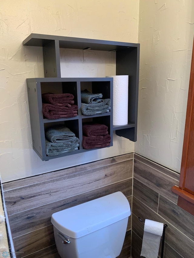 interior details featuring toilet and a textured wall