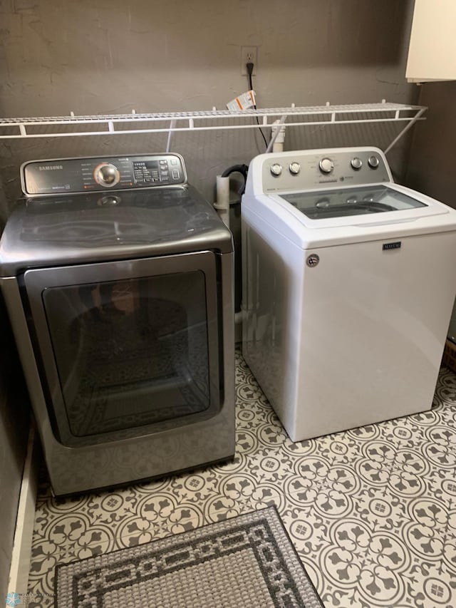 clothes washing area featuring laundry area, light tile patterned floors, and washing machine and clothes dryer