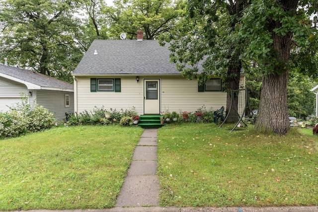 view of front of home with roof with shingles, a chimney, and a front lawn