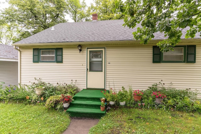 view of front of house with a shingled roof and a chimney