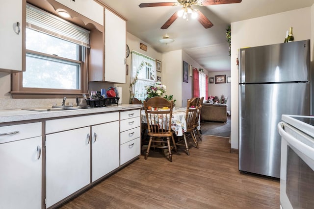 kitchen with electric stove, light countertops, freestanding refrigerator, white cabinets, and wood finished floors