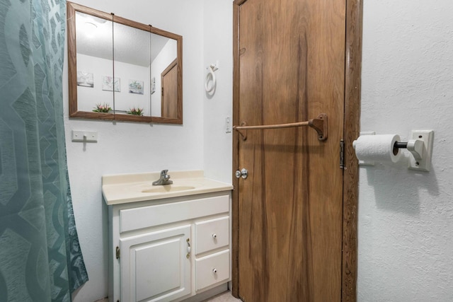 full bath with a textured wall and vanity