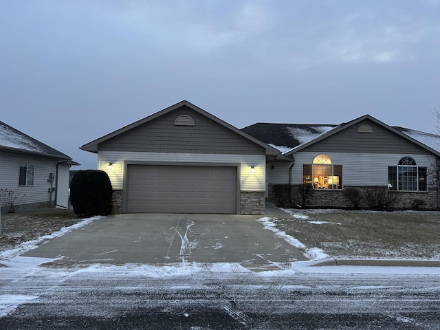 ranch-style house featuring an attached garage, stone siding, and concrete driveway