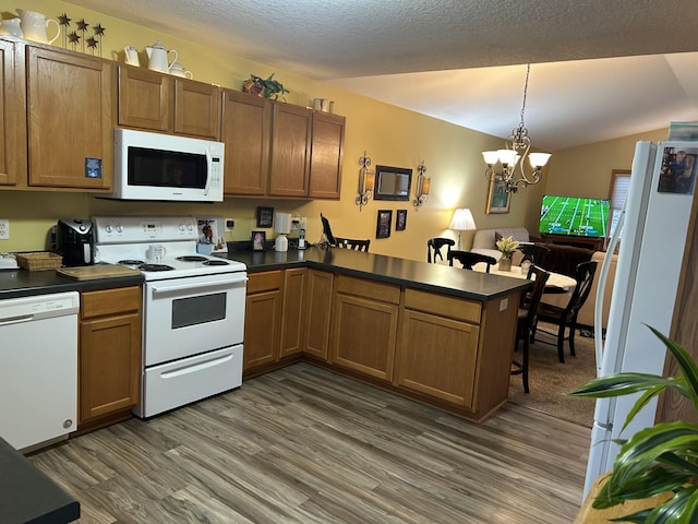 kitchen featuring dark countertops, white appliances, a peninsula, and dark wood-style flooring