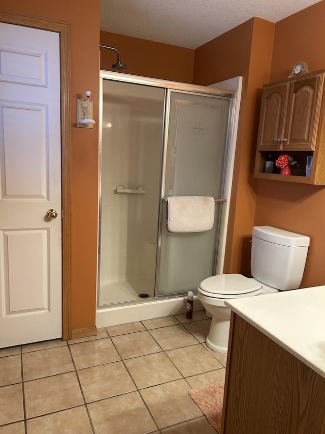 bathroom featuring a textured ceiling, toilet, vanity, a shower stall, and tile patterned floors