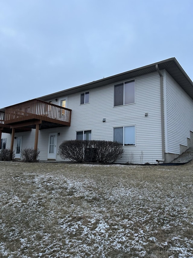 snow covered rear of property with a wooden deck