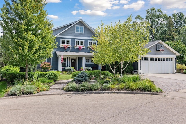 view of front of property featuring driveway, an attached garage, and covered porch