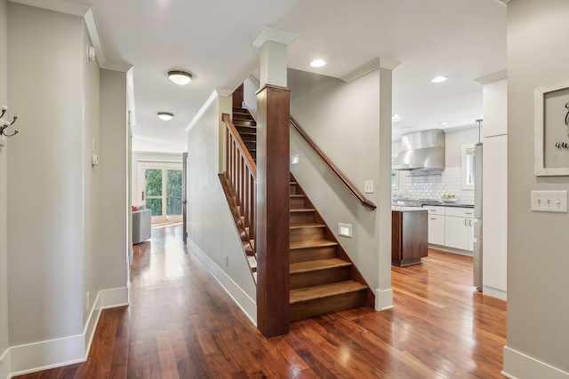 stairway with baseboards, recessed lighting, wood finished floors, and crown molding