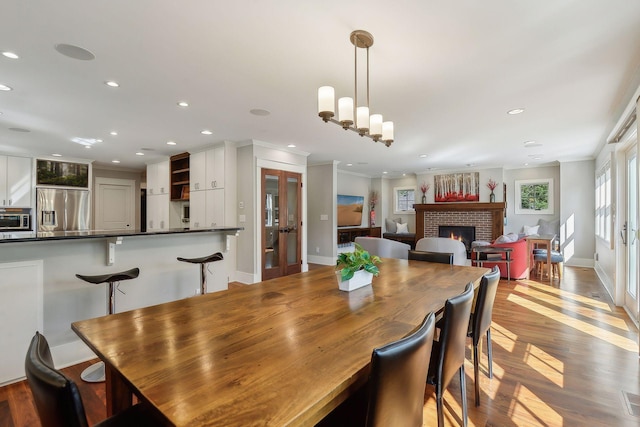 dining area with recessed lighting, a fireplace, baseboards, french doors, and wood finished floors