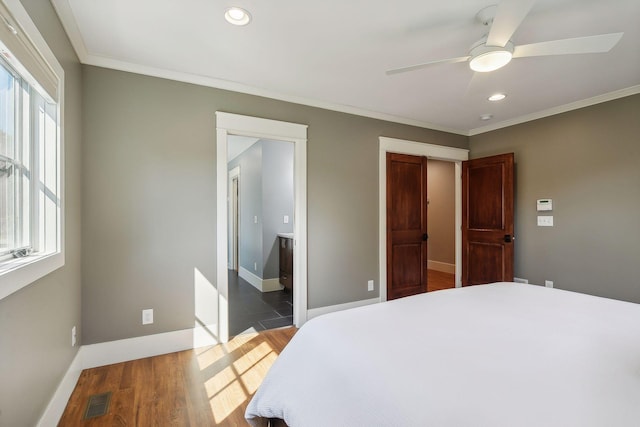 bedroom with ornamental molding, wood finished floors, visible vents, and multiple windows