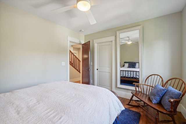 bedroom with baseboards, wood finished floors, ceiling fan, and a closet