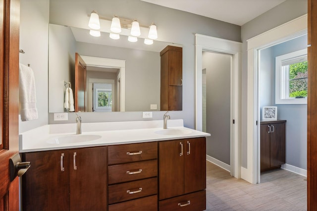 full bathroom featuring double vanity, baseboards, and a sink