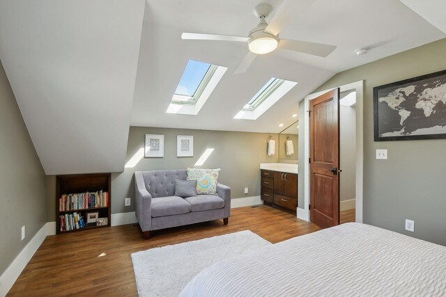 bedroom with baseboards, a ceiling fan, vaulted ceiling with skylight, and dark wood-type flooring