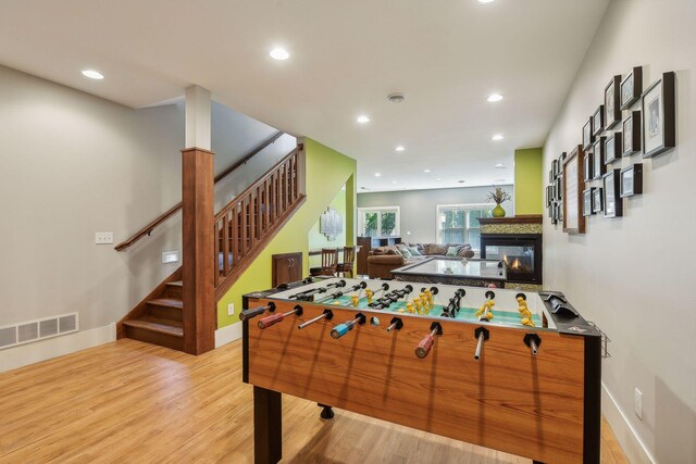 rec room with recessed lighting, a multi sided fireplace, light wood-type flooring, baseboards, and visible vents
