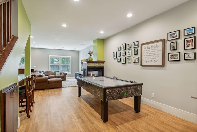 recreation room with baseboards, a multi sided fireplace, light wood-type flooring, and recessed lighting