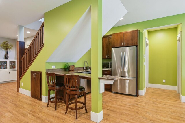kitchen with baseboards, light wood-type flooring, appliances with stainless steel finishes, and recessed lighting