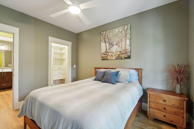 bedroom with ensuite bath, ceiling fan, and light wood finished floors
