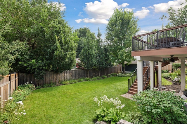 view of yard featuring ceiling fan, a fenced backyard, and stairs