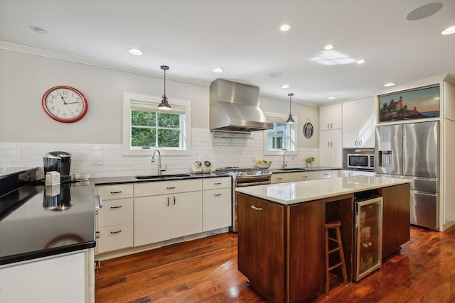 kitchen with island range hood, beverage cooler, stainless steel appliances, and a sink