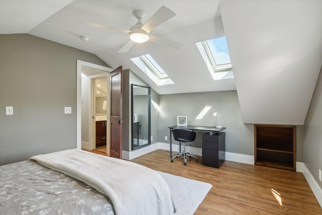bedroom with a ceiling fan, vaulted ceiling with skylight, wood finished floors, and baseboards