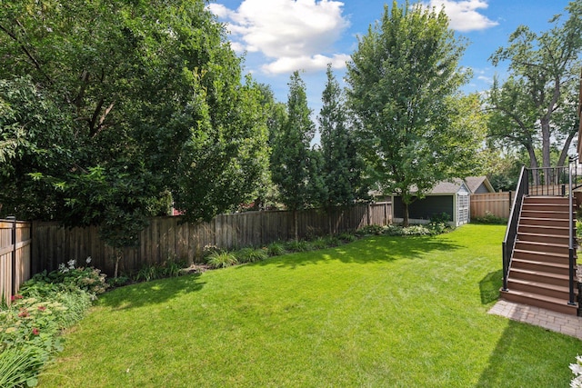 view of yard featuring stairway, a fenced backyard, and an outbuilding