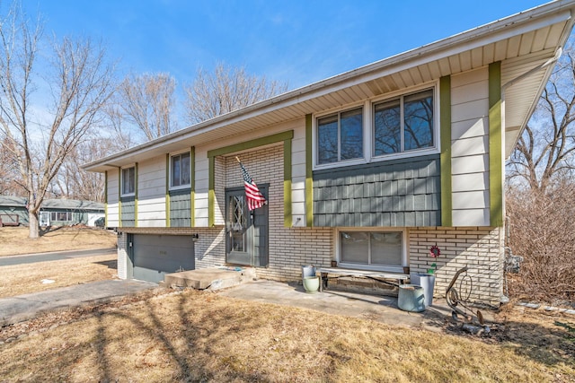 split foyer home featuring brick siding, an attached garage, and driveway