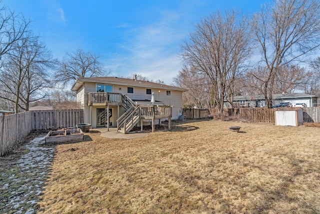 rear view of property with a yard, a wooden deck, a fenced backyard, and a garden