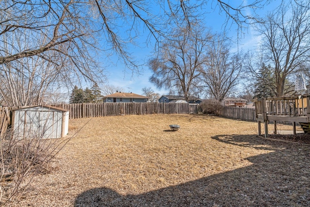 view of yard with a deck, an outdoor structure, a fenced backyard, and a shed