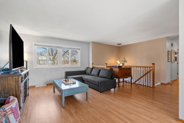 living room with visible vents, light wood-style flooring, and baseboards