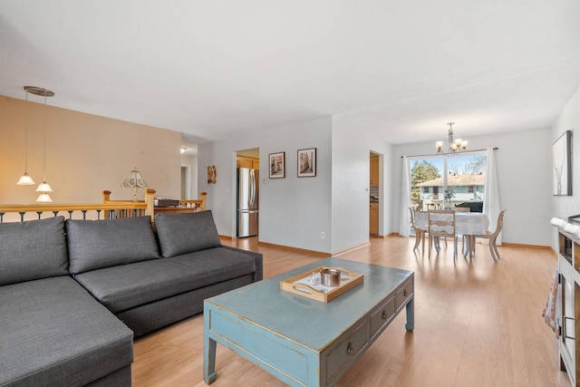 living room featuring light wood-type flooring, baseboards, and a chandelier